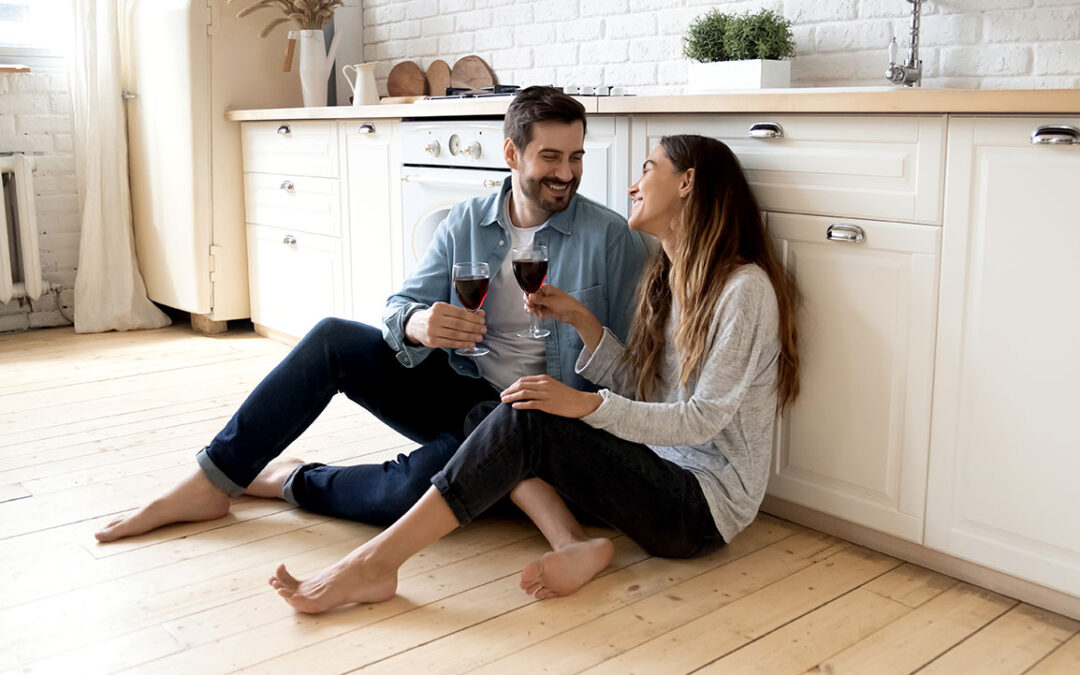 A couple sitting on a beautiful hardwood floor solution provided by Woodcraft Flooring